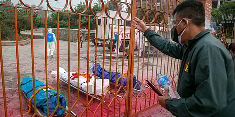 A family member pays his last tribute to bodies of COVID-19 victims before cremation near Pashupatinath temple in Kathmandu, Nepal. (Photo | AP)