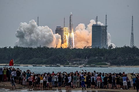People watch a Long March 5B rocket, carrying Tianhe space station core module, as it lifts off from the Wenchang Space Launch Center in China. (Photo | AFP)