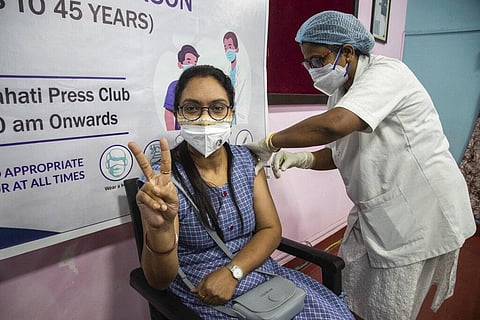 A young journalist receiving a shot of COVAXIN gestures to camera as she gets vaccinated against coronavirus at the press club in Gauhati. (Photo | AP)