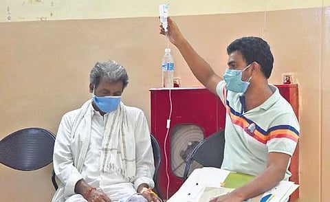A patient infected by black fungus waits for a bed at Government ENT Hospital, Koti, while his attendant holds a saline bottle, in Hyderabad on Wednesday.