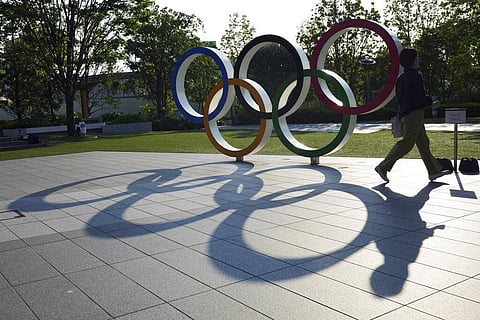A woman walks by the Olympic Rings near the National Stadium in Tokyo Wednesday, June 9, 2021. (Photo | AP)