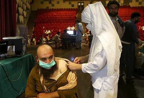 A government employee receives the Convidecia COVID-19 vaccine from a paramedic at a vaccination center in Nishtar hall, in Peshawar, Pakistan. (Photo | AP)