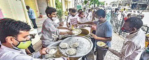 Volunteers distribute free food near Hanuman temple at Hazratganj in Lucknow (Photo | PTI)
