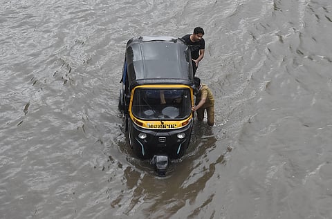 People push an auto rickshaw as they wade through a waterlogged street as heavy rain continues, at Sion in Mumbai. (Photo | PTI)
