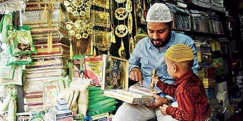 A shopkeeper teaches a child how to read the Quran the ‘technological’ way, near Charminar in Old City on Tuesday. Image used for representational purposes. (Photo | Vinay Madapu, EPS)