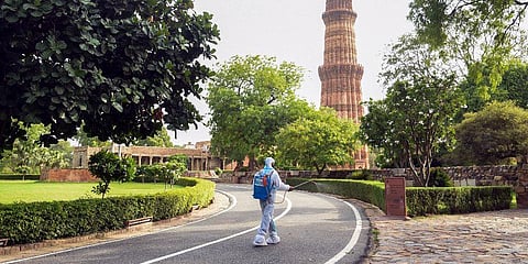 A worker sprays sanitizer inside Qutub Minar premises as the state government allows the re-opening of monuments, in New Delhi. (Photo | PTI)