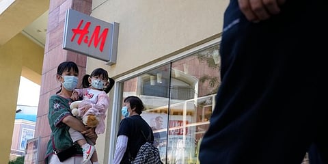 A woman and child wearing masks pass by a H&M store in Beijing on Thursday, June 3, 2021. (Photo | AP)