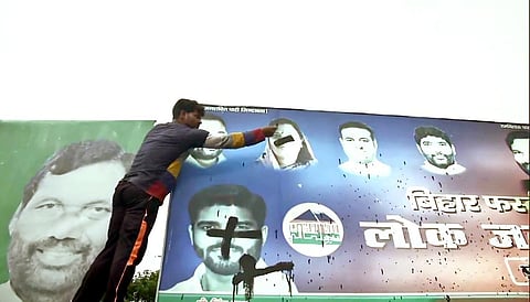 A supporter of Chirag Paswan smear black ink on the poster of 5 LJP MPs outside the party's office, in Patna. (Photo | ANI)