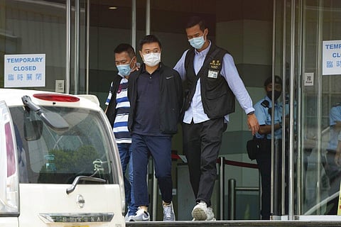 Police officers escort Ryan Law, Apple Daily's chief editor, at Apple Daily headquarters in Hong Kong. (Photo | AP)