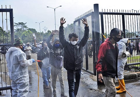 Soldiers in protective suits spray disinfectant on people entering the Gelora Bandung Lautan Api Stadium to receive the Sinovac COVID-19 vaccine in Indonesia. (Photo | AP)