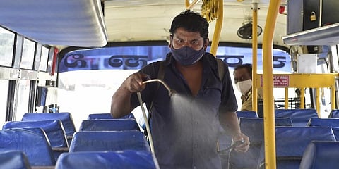 A worker sprays disinfectants inside a state road transport bus ahead of its re-opening after certain restrictions of COVID-induced lockdown were eased, in Bengaluru. (Photo | PTI)