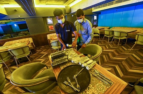 Workers arrange crockery at a restaurant in Connaught Place ahead of its reopening, as part of government's order of gradual unlocking of COVID-induced restrictions. (Photo | PTI)