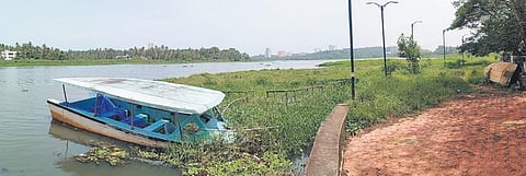 The Akkulam lake filled with water hyacinths and garbage. A sunken boat near the Akkulam Boat Club, which has been shut for a long time | B P Deepu