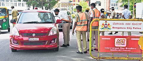 Police stop motorists at a checkpoint during the state-wide lockdown in Bengaluru on Saturday. (Photo | Vinod Kumar T/EPS)