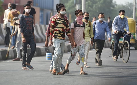 Workers leave for their jobs as shops and offices reopen after further ease in the COVID-19 lockdown, in New Delhi, Monday. (Photo | PTI)