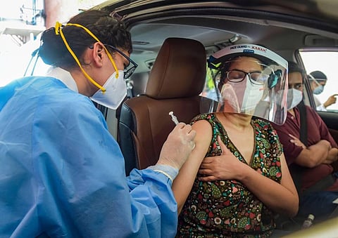 A health worker administers a dose of the COVID-19 vaccine to a woman at a drive-through vaccination centre in New Delhi. (File Photo | PTI)