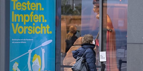 A woman wearing a face mask walks past a garment retail shop in Berlin. (File photo| AFP)