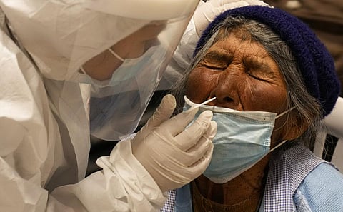 A health worker administers a COVID-19 test to an elderly woman at a cable car station in El Alto, Bolivia (Photo | AP)