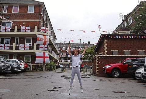 Marianne Hicks-Brisson jumps in the air as she poses for a photograph in the Kirby Estate adorned with English Cross of St. George flags in support of the England soccer team. (Photo | AP)