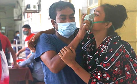 A man assists a patient facing difficulties in breathing at the Medical College Hospital in Rajshahi, Bangladesh (Photo | AP)