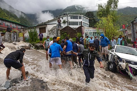 People place rocks to divert sudden gush of water during flash floods after heavy monsoon rains in Bhagsunag, a popular tourist town in Himachal Pradesh. (Photo | AP)