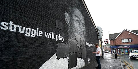 Ed Wellard, from Withington, tapes bin liners across offensive wording on the mural of England striker Marcus Rashford on the wall of the Coffee House Cafe on Copson Street. (Photo | AP)