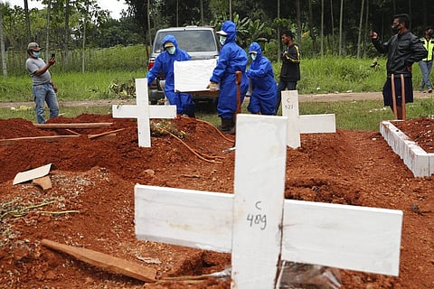 Workers in protective suits carry a coffin containing the body of a COVID-19 victim to a grave for a burial at Cipenjo cemetery in Bogor, West Java, Indonesia (Photo | AP)