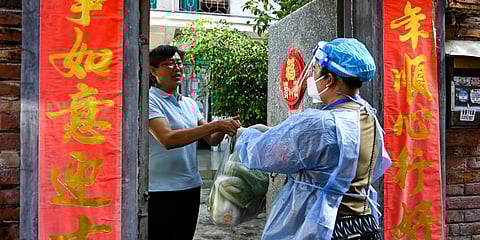 A community worker delivers daily necessities to a household under closed-off management in the city of Ruili in southwestern China's Yunnan Province. (Photo| AP)