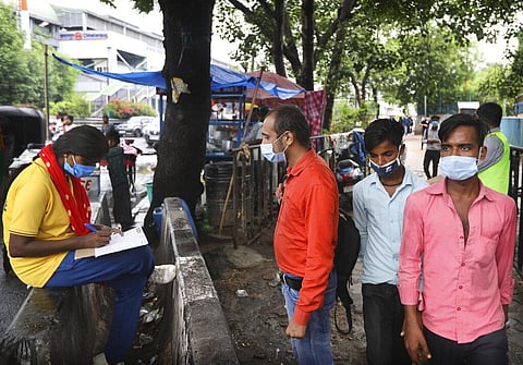 A health worker registers people for the COVID-19 test near a metro station, in New Delhi. (Photo | AP)