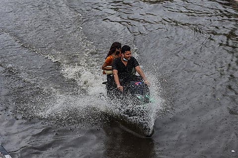 A man rides a motorcycle on a waterlogged road after heavy rains in New Delhi. (Photo | PTI)