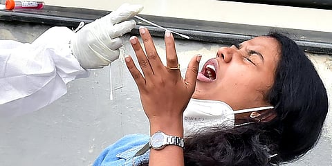 A healthcare worker takes a swab sample of a woman for the COVID-19 testing, in Bengaluru. (Photo| ANI)