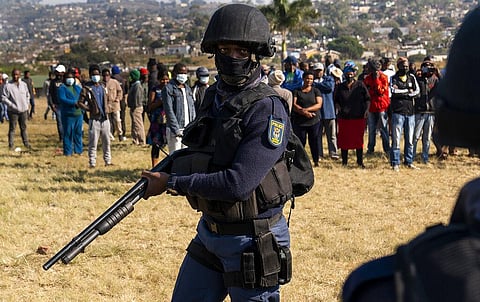 An armed policeman patrols as Police Minster Bheki Cele visits Phoenix, a neighbourhood severely affected by unrest and racial tensions near Durban, South Africa. (Photo | AP)