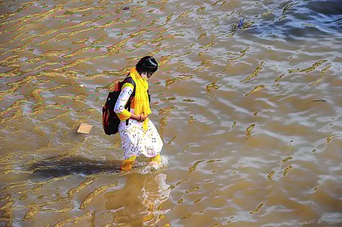 A commuter wades through a waterlogged street following heavy rains at Nalasopara in Palghar district. (Photo | PTI)