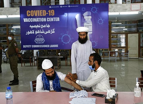 A student receives the Convidecia COVID-19 vaccine from a health worker at a vaccination center setup in Jamia Naeemia, an Islamic University in Lahore. (Photo | AP)