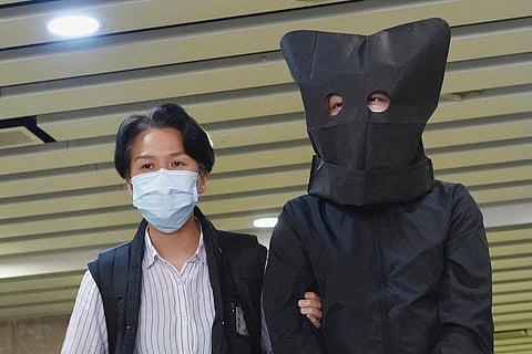 A suspect is escorted by a police officer to search evidence at an office in Hong Kong. (Photo | AP)