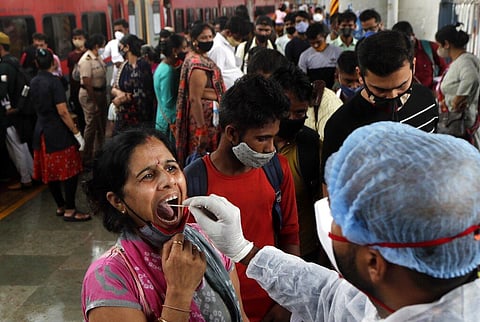 A health worker collects a swab sample from a traveler to test for COVID-19 at a train station in Mumbai. (Photo | AP)