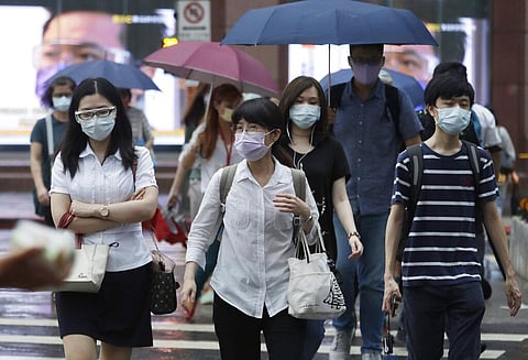 People wearing face masks to protect against the spread of the coronavirus walk in the light rain from approaching Typhoon In-Fa in Taipei, Taiwan. (Photo | AP)