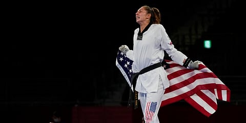 US' Anastasija Zolotic celebrates as she holds her country's national flag after winning a gold medal for the taekwondo women's 57kg match at the 2020 Summer Olympics in Tokyo, Japan. (Photo | AP)