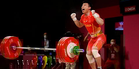 Chen Lijun of China celebrates after winning the gold medal and setting an Olympic record in the men's 67kg weightlifting event, at the 2020 Summer Olympics in Tokyo, Japan. (Photo | AP)