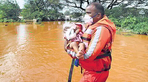 An NDRF rescuer carries an infant in a heavily flooded area in Kohlapur district in Maharashtra. (Photo | PTI)