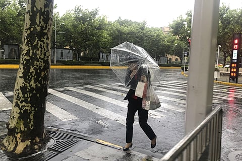 A woman carrying an umbrella braces against the wind and rain as Typhoon In-fa sweeps through Shanghai in China Sunday, July 25. (Photo | AP)