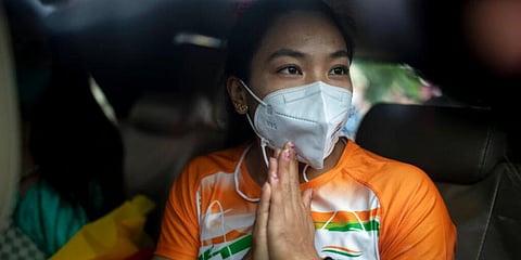 Indian weightlifter Mirabai Chanu who won the silver medal in Tokyo Olympics makes a Namaste gesture as she prepares to leave in a car after arriving at the airport in New Delhi, India. (Photo | AP)