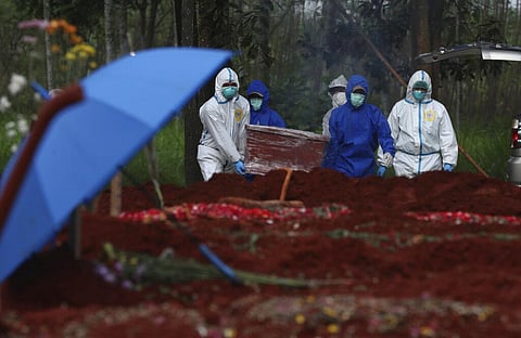 Workers in protective suits carry a coffin containing the body of a COVID-19 victim to a grave for burial at Cipenjo cemetery in Bogor, West Java, Indonesia. (Photo | AP)