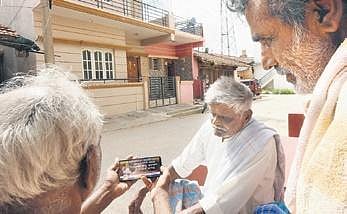 Residents of Bookanakere watch Yediyurappa’s speech after resignation on a mobile phone | Udayashankar S