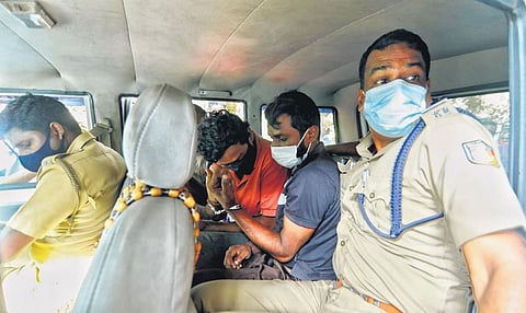 Police taking away the accused as a crowd gathers