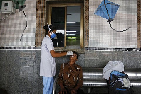 A health worker takes a swab sample of a passenger entering the city to test for COVID-19, at a railway station in Ahmedabad. (File Photo | AP)