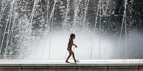 A girl walks on the edge of a fountain on a hot day in downtown Skopje, North Macedonia. (Photo | AP)