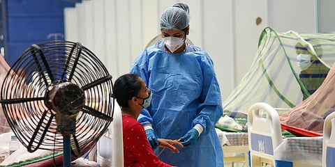 (Representational image) An healthcare worker in PPE kit treats COVID-19 patient at CWG COVID care center, in New Delhi. (Photo| ANI)