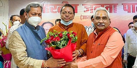 Newly elected Uttarakhand CM Pushkar Singh Dhami (C) with former CM TS Rawat (L) and BJP state President Madan Kaushik, in Dehradun. (Photo | PTI)