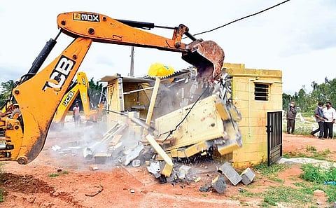 An earthmover razes an illegal structure in the proposed Karanth Layout